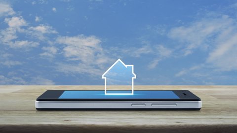 House icon with copy space on modern smart mobile phone screen on wooden table over blue sky with white clouds, Businesss real estate online concept