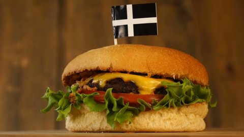 Delicious burger with small flag of Saint Pirans on top of them with toothpicks. Yummy juicy hamburger rotating.