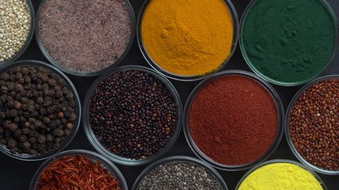 Different spices and herbs on background rotating, close up, top view. Assortment colorful spices, seeds and herbs for cooking food