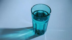 A man's hand throws a soluble pill into blue glass of water. The tablet fizzes and dissolves. Healthycare and medicine concept