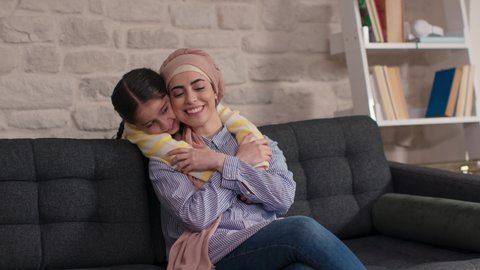 Little girl hugging her mother, having fun together and laughing. Mother hugging her child having a good moment in the living room at home.