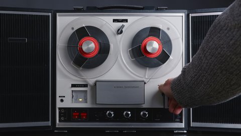 Man hand turns on music on reel to reel tape recorder playing. Rotating vintage music player close up. Retro tape. Spinning reel. Party. Loop. Front view. Front view. Popular Disco Trends 60s, 70s, 80