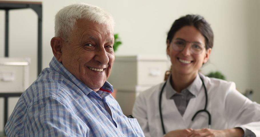 Older male patient and doctor on background smile looking at camera sit in clinic office. Portrait of satisfied hospital client, reliable high quality professional eldercare, medical insurance concept | Shutterstock HD Video #1064113021