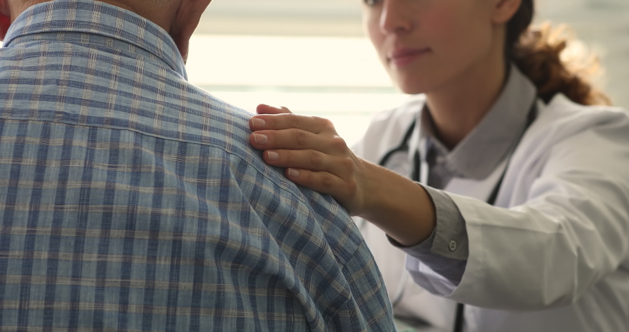 Therapist during pep talk put arm on older 70s male patient shoulder, close up. Eldercare, gerontology, bad news, express empathy, consoling of aged man before course of treatment for disease concept Royalty-Free Stock Footage #1064113126