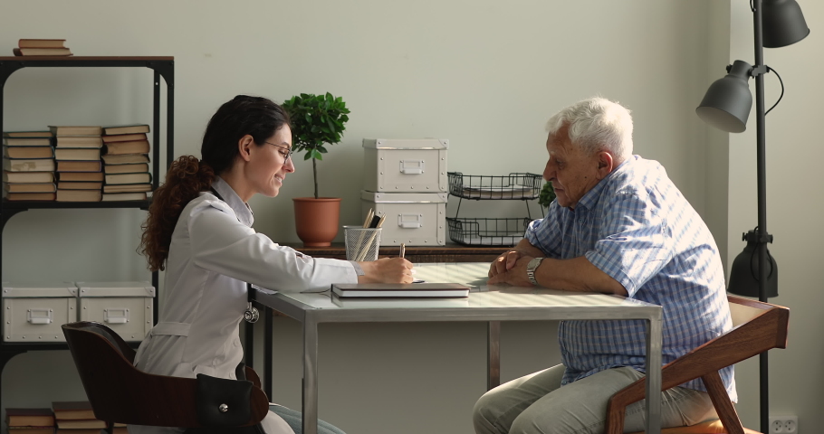 35s female professional physician consulting to older male patient, talking to senior man in clinic during medical health check up. Geriatric diseases treatment, caregiving, elderly healthcare concept Royalty-Free Stock Footage #1064113180