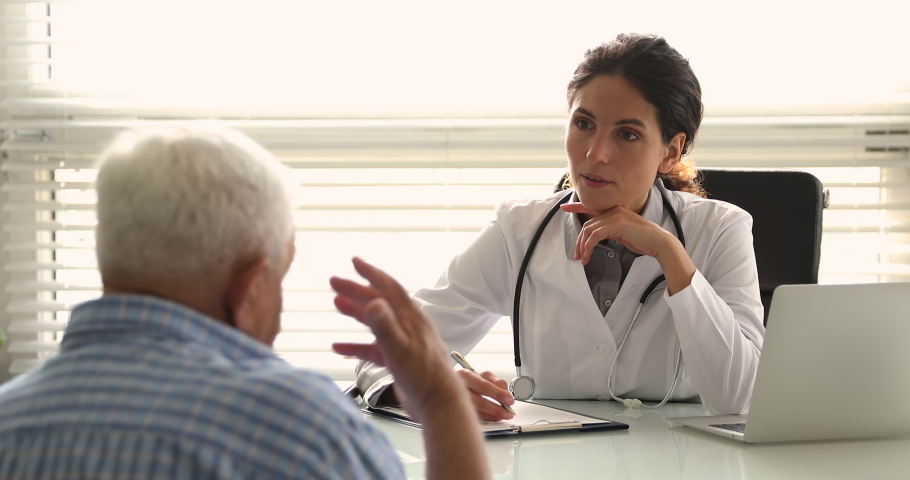 Young woman doctor in white uniform and stethoscope on neck talk to older patient, discuss health concerns writes complaints, fill medical form. General check up, healthcare, medical insurance concept | Shutterstock HD Video #1064113504