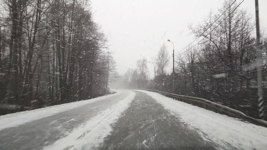 View through the windshield on the highway in winter along which the car is driving in heavy snow and wind in Russia. Royalty-Free Stock Footage #1064117839