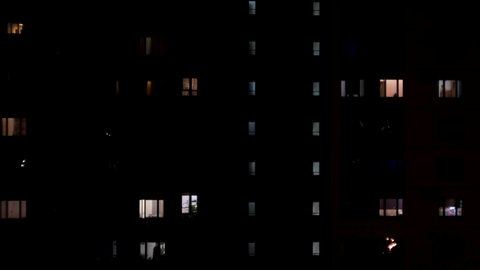 Night view of lights in window of the multi-storey building. Concept. Multi-storey house with apartments late in the evening, concept of night life.