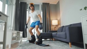 Fun video. Man in shorts and a T-shirt depicts snowboarding on a carpet in a cozy room. Waiting for a snowy winter.