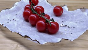 4k. Cherry tomatoes close-up. Red small cherry tomatoes on paper and bamboo wood board, background video.