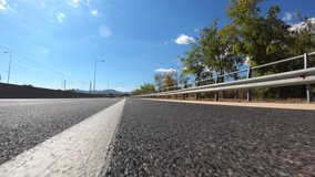 Fast moving video of national road with clear blue skies taken by stabilised camera attached to motorcycle as seen from asphalt road perspective 