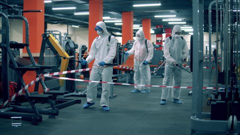 Group of experts are disinfecting fitness center