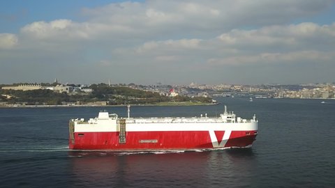 ISTANBUL - CIRCA 2020: Ro-Ro ship sails past the Old Istanbul City. Aerial. Pure car and truck carrier underway in Bosphorus Sea. Vehicles carrier in front of the Sarayburnu Coast
