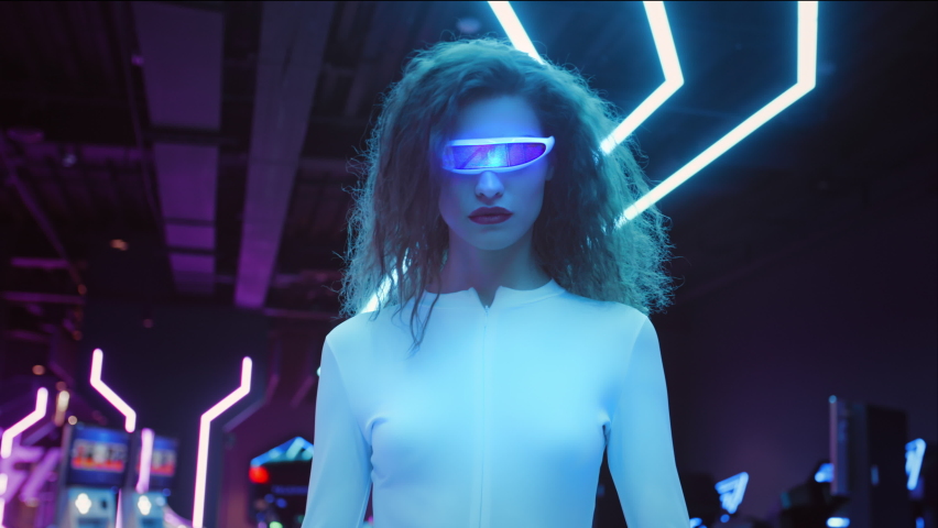Fashion young woman in futuristic glasses and white suit walk in night club in city. Blue and violet neon lights. AR hybrid reality, future technology, augmented reality, entertainment, sci-fi concept Royalty-Free Stock Footage #1064129494