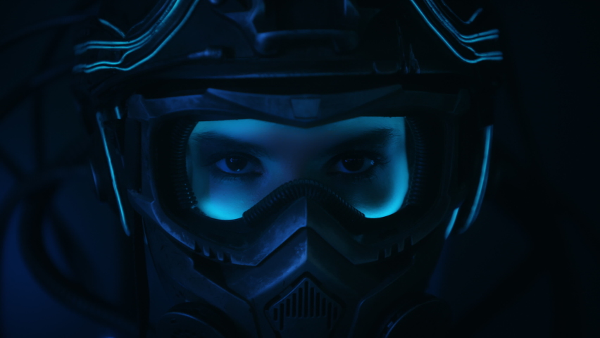 Portrait female soldier of future in fiction helmet open her eyes looking into camera standing on black background at night. Woman in futuristic combat costume. Cyberpunk style warrior | Shutterstock HD Video #1064129500