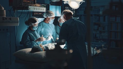 Multi-ethnic cooperating team of doctors and surgeons processing surgical operation in operating room modern hospital emergency department. Heart surgery.