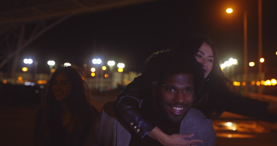 Girl piggyback rides friend at night on streets after party