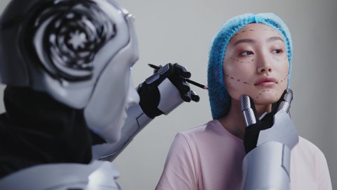 Robotic cosmetologist cyborg drawing lines on asian female customer face for beauty procedure surgical operation lifting procedure against backround. Future concept.