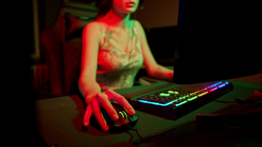 Sexy young woman with many tattooes playing game in neon gaming club