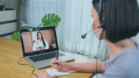 Asian young woman video call with doctor in living room at home. Patient girl consulting with general practitioner application computer laptop. Doctor and Consultant online and telemedicine concept.