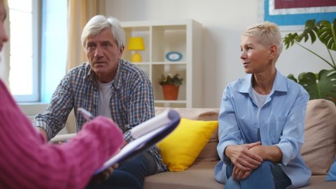 Unhappy senior husband talking to psychologist counselor complaining about bad relationship with wife. Aged couple having relationship problem visiting therapist office