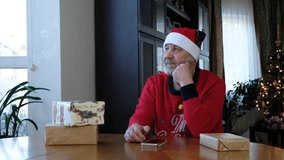 beared senior man in red christmas hat talking on the smart phone, video call
