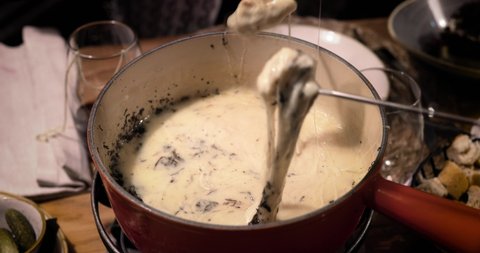 Close up od a cheese fondue. We can see the bread soak in the melted cheese. Perfect meal with friends 4K