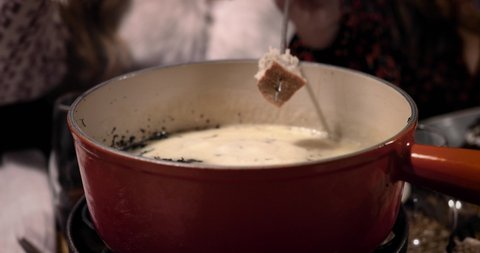 Cheese fondue in close up. We can see the bread soak in the melted cheese. Perfect meal with friends 4K