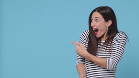 Amazed surprised brunette young woman 20s wearing basic striped shirt posing isolated on blue color background studio. People lifestyle concept. Pointing index finger aside showing thumbs up say wow - Powered by Shutterstock - Get 15% off with code: PIKWIZARD15