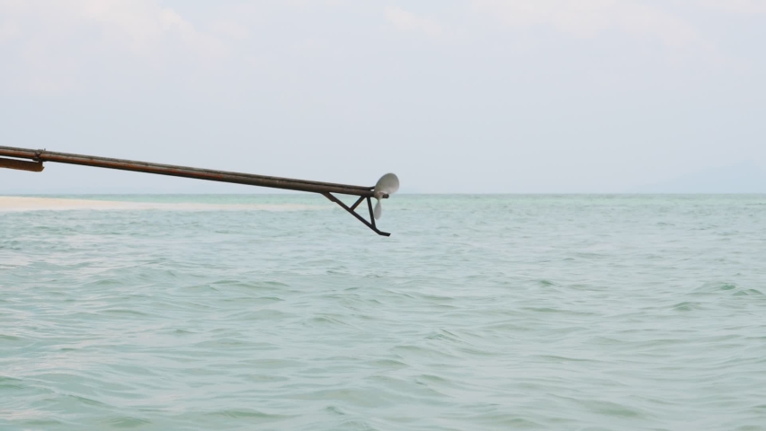 Driving propeller on long rod, propulsion device of long-tail boat, popular small watercraft widely used at Thailand. Prop rotate quickly and immersed in sea water with splashes backwards