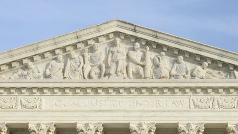 'Equal Justice Under Law' engraved on the west pediment of the United States Supreme Court Building in Washington, D.C. as seen on a sunny day. No people.