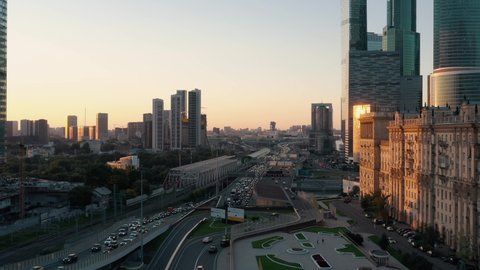 Heavy traffic near business centre with skyscrapers, drone flying over the road. Moscow city traffic in the evening sunset, cars on the highway road near Moscow business centre