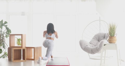 Sporty young black woman making squats training at home. Athletic fit girl doing fitness aerobic exercises for booty in living room. Home fitness and wellness concept.