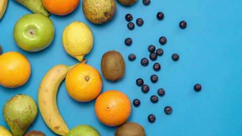 Fresh fruits moving on blue background. Stop motion