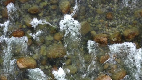 Top view of a mountain river full with boulders and crystal clear water
