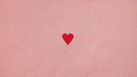 4K stop motion video of heart beating concept. Red paper heart on the pink background. Valentine's Day.