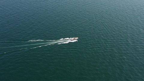 Aerial view of luxury white boat fast movement on water. White large yacht at high speed in the sun. Aerial view. People on the boat.