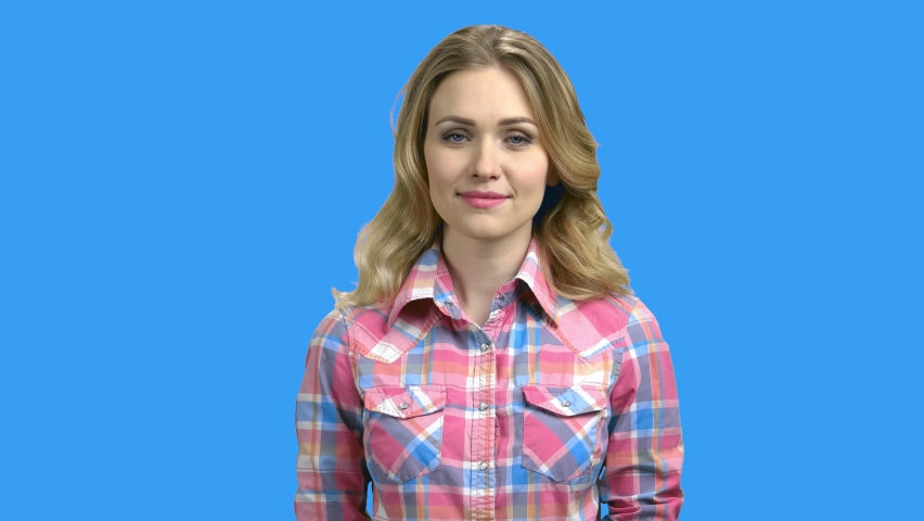 Portrait of beautiful smiling woman on color background. Pretty cucasian girl looking at camera while standing on blue background.