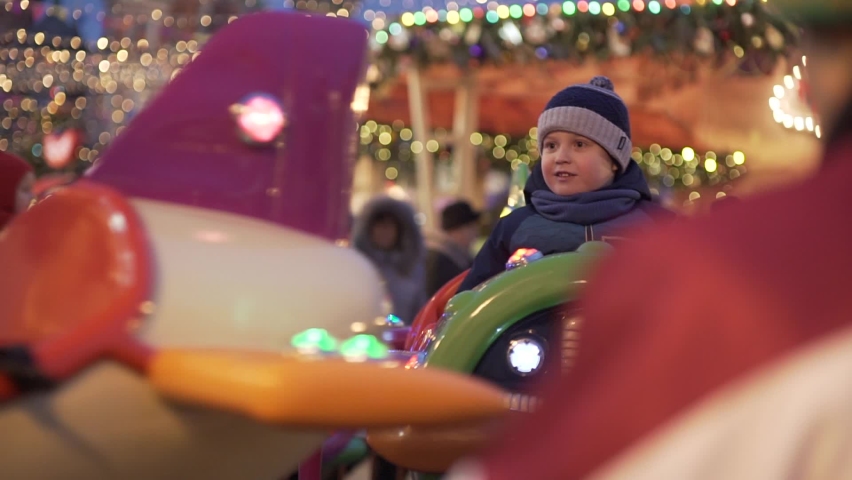 Moscow, Russia December 15, 2019: Holiday decoration on Manezhnaya Square, Moscow city, Russia. Fair near Kremlin. Party mood. Happy little boy on carousel. Roundabout with horses. Enjoying the ride | Shutterstock HD Video #1064184835
