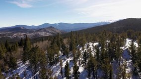 High definition aerial video flying over snowy Rocky Mountain forest.