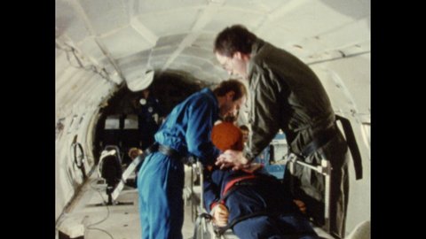 1980s: men in jumpsuits perform CPR on mannequin in microgravity on plane, open equipment pack, man adjusts knobs on wall of computers, medical and computer equipment, women in lab coats work at table
