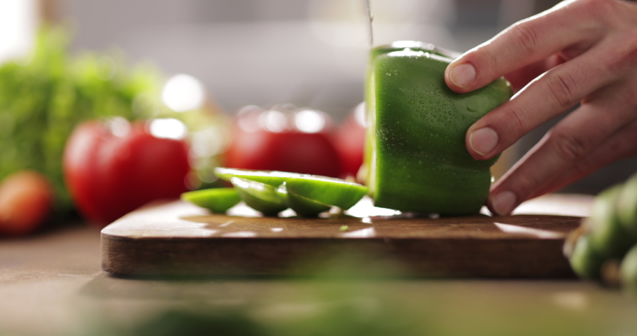 Close up shot of chef's hands using a knife cutting a fresh bell pepper on wooden board. Cooker preparing a vegetarian meal - food and drink 4k footage Royalty-Free Stock Footage #1064192230