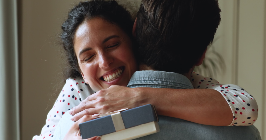 Head shot close up happy millennial woman embracing boyfriend, holding wrapped package gift in hands, feeling grateful. Smiling young caucasian wife thanking husband for surprise present, showing love Royalty-Free Stock Footage #1064201506