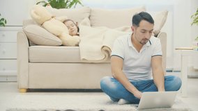 Father is online while his daughter is sleeping on a background in 4k slowmotion video.