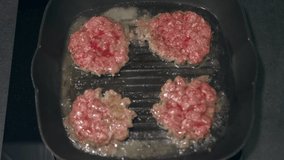 Four beef patties are fried in a pan. Smooth collision