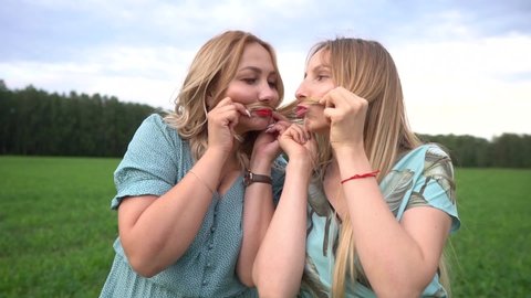 portrait of two girls having fun and make faces with moustaches out of their hair.Two friends have fun.Two happy friends
