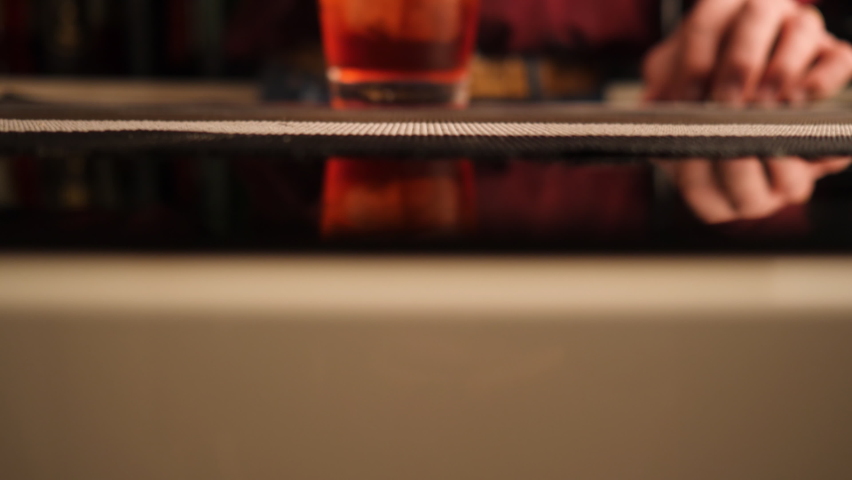 Bartender serves a Negroni cocktail on the bar counter. Royalty-Free Stock Footage #1064221615