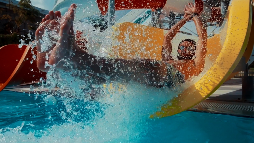 Happy Cheerful Male On Holiday Resort. Summer Vacation Enjoying On Waterslide. Funny Ride On Water Slide Pool In Water Park. Sliding Down In Waterpark. Man Having Fun On Water Slides Aqua Park Glides Royalty-Free Stock Footage #1064223502