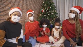 African American black family, women and kid girl daughters with face masks sharing gifts on Merry Christmas Eve Xmas Party. They talking video call online Celebration in covid 19 coronavirus pandemic