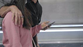 Close-up of a young interracial couple walking embraced in a subway corridor, talking and laughing about something they are seeing on their smart phone. - Powered by Shutterstock - Get 15% off with code: PIKWIZARD15